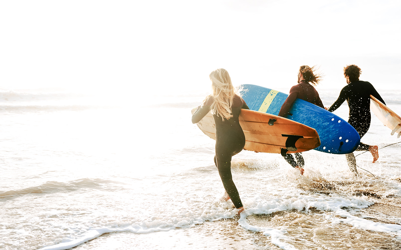 Surfers entering ocean with boards on Road to Hana, Maui, Hawaii.