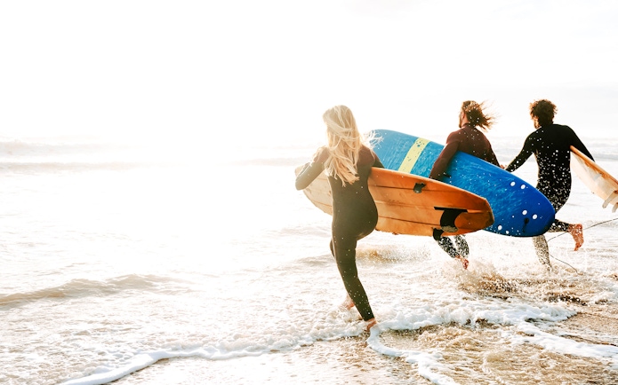 Surfers entering ocean with boards on Road to Hana, Maui, Hawaii.