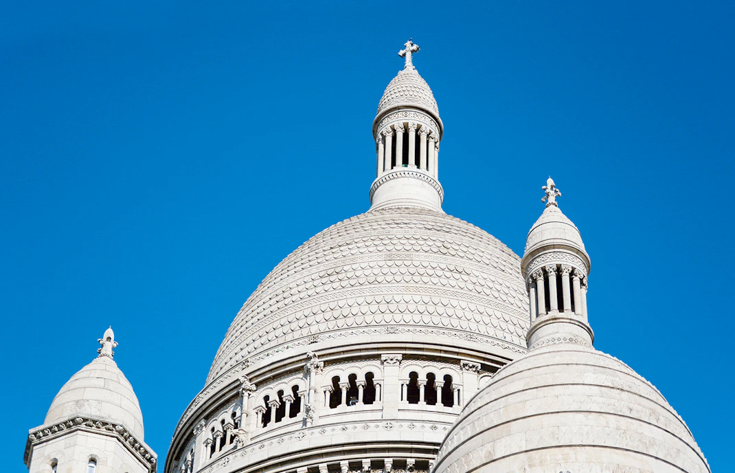Dome of Sacré-Cœur Basilica against a clear blue sky in Montmartre, Paris.