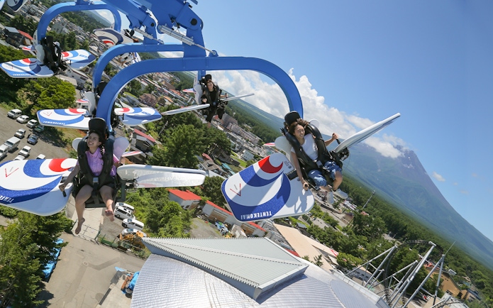 Visitors enjoying a thrilling ride at FujiQ Highland with Mount Fuji in the background.