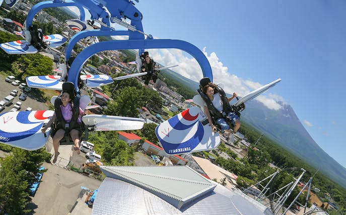 Visitors enjoying a thrilling ride at FujiQ Highland with Mount Fuji in the background.