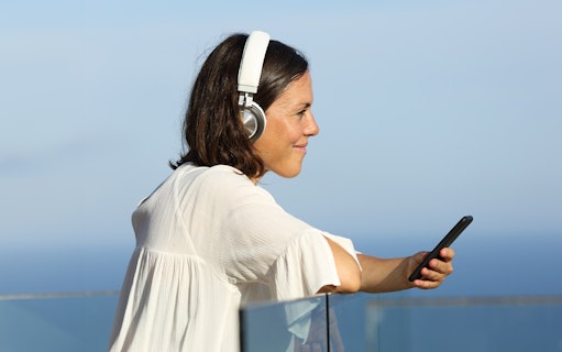 Woman listening to audio guide on cruise deck with ocean view.