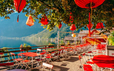 Lakeside cafe with red lanterns and chairs overlooking Hallstatt lake, Austria.