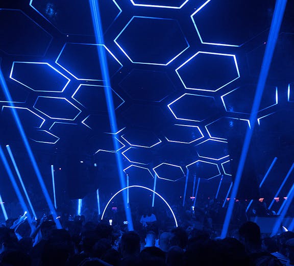 Crowded dance floor at Pacha nightclub with blue hexagonal ceiling lights.