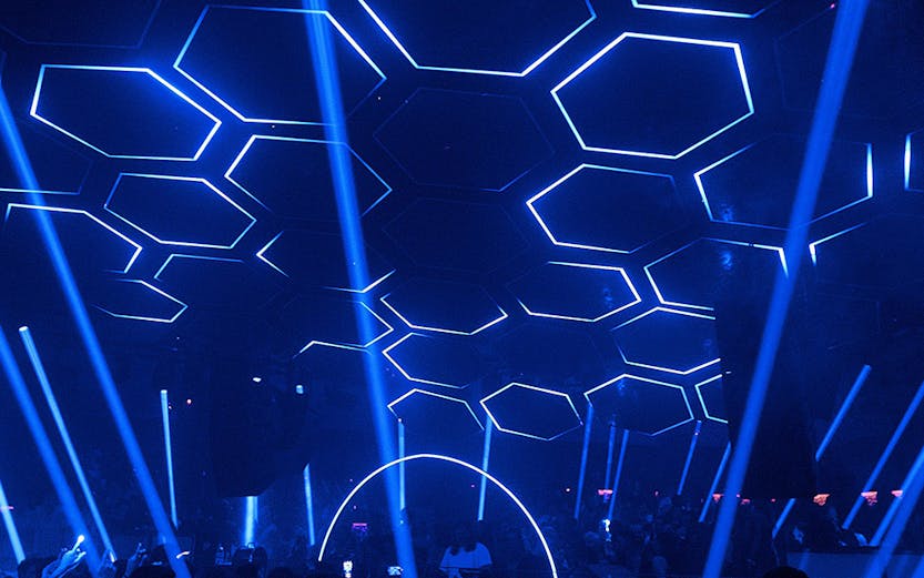 Crowded dance floor at Pacha nightclub with blue hexagonal ceiling lights.