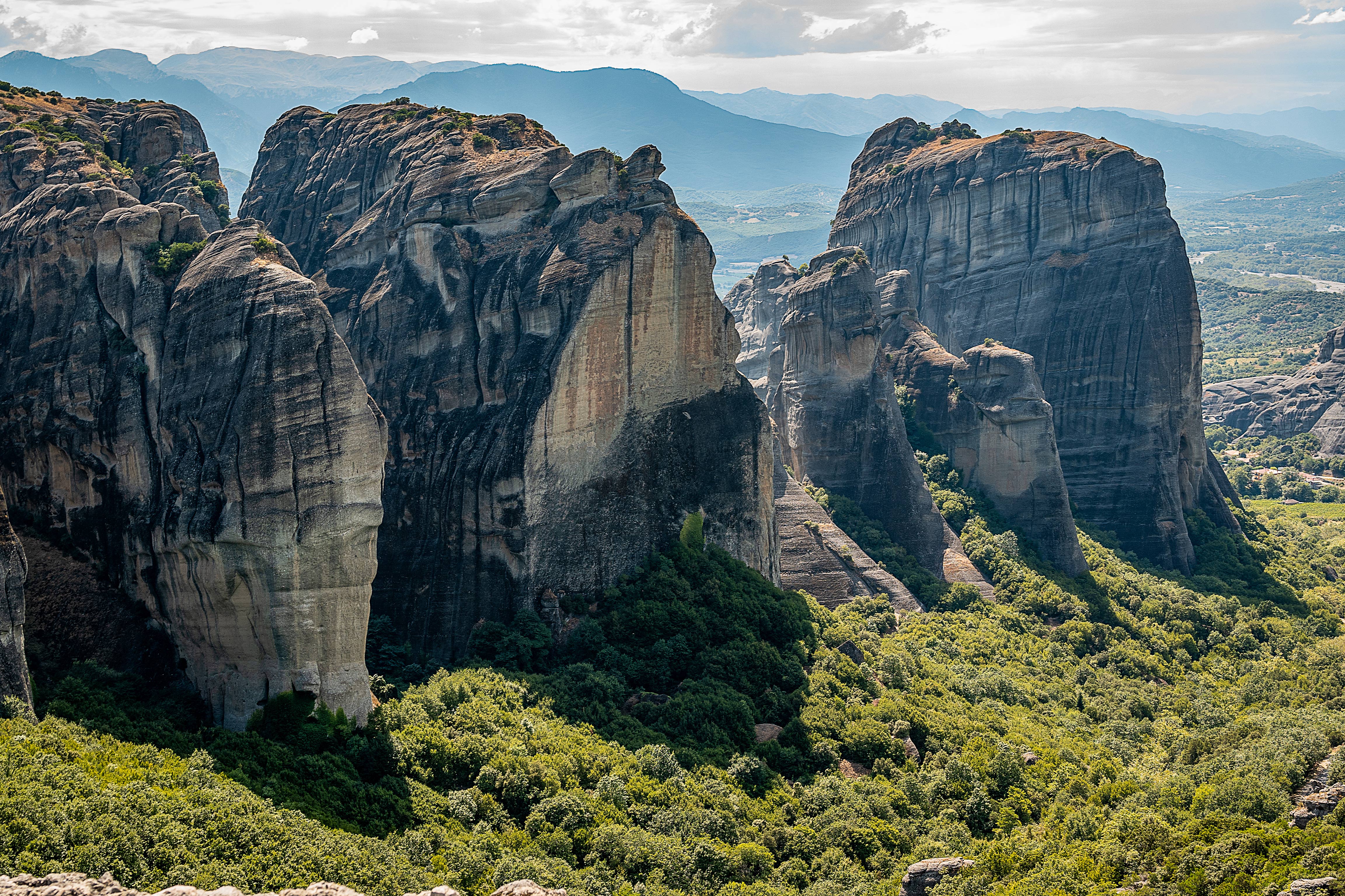 Meteora rock formations in Greece, featuring the Holy Spirit Rock amidst lush greenery.