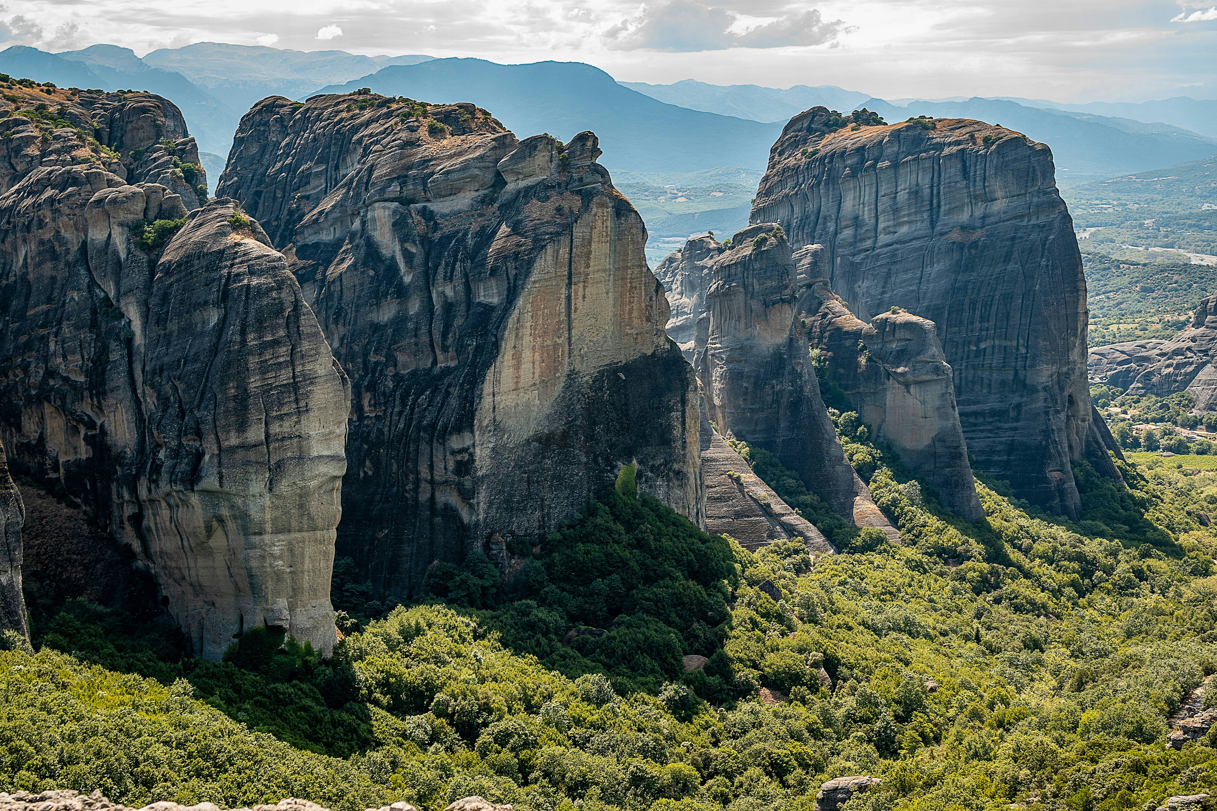 Meteora rock formations in Greece, featuring the Holy Spirit Rock amidst lush greenery.