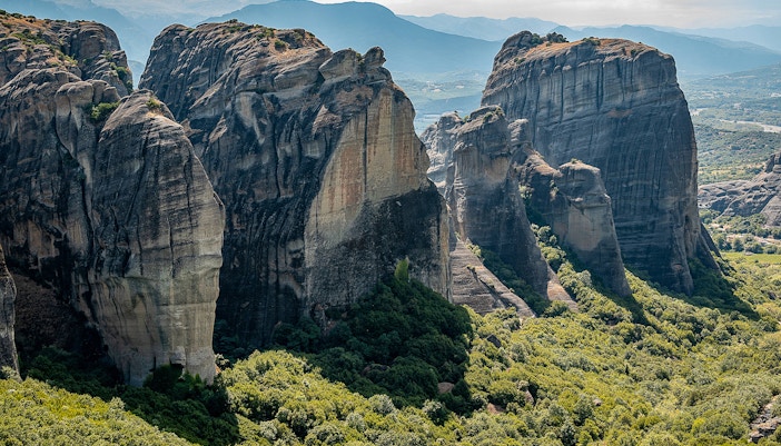 Meteora rock formations in Greece, featuring the Holy Spirit Rock amidst lush greenery.
