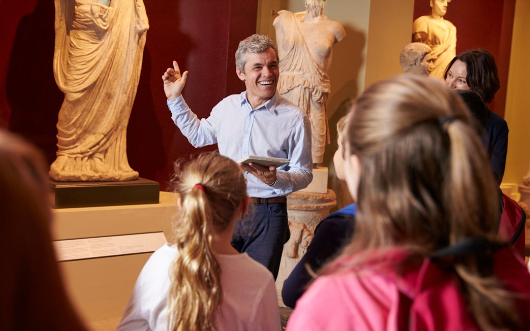 Visitors on a guided tour at the British Museum, viewing ancient sculptures.