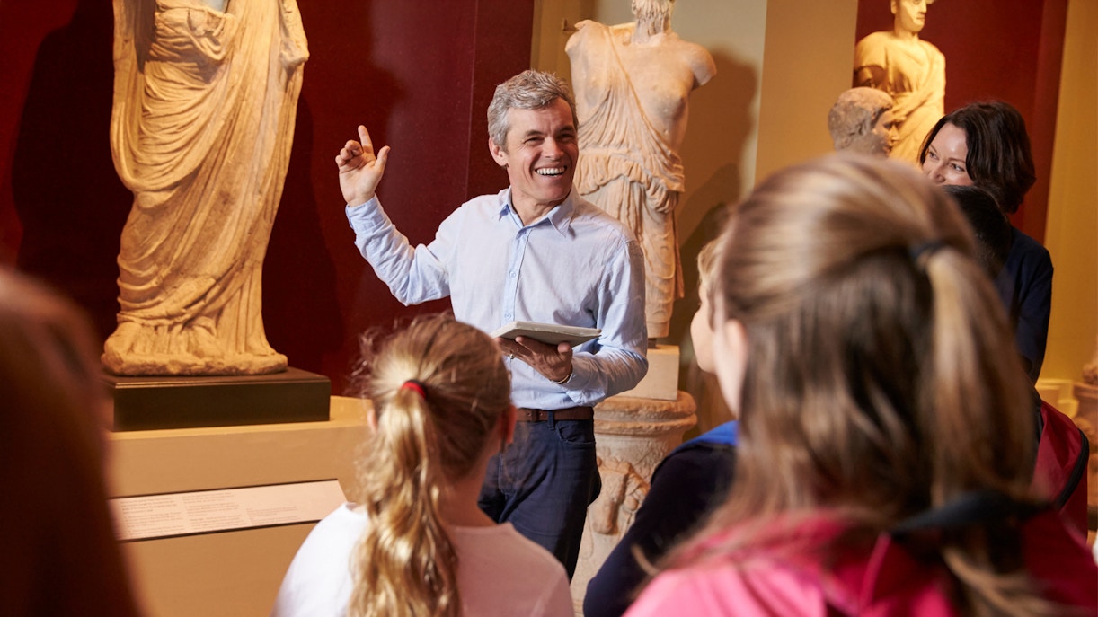 Visitors on a guided tour at the British Museum, viewing ancient sculptures.