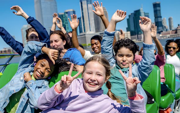 Guests enjoying NYC Speedboat Ride with skyline in background.