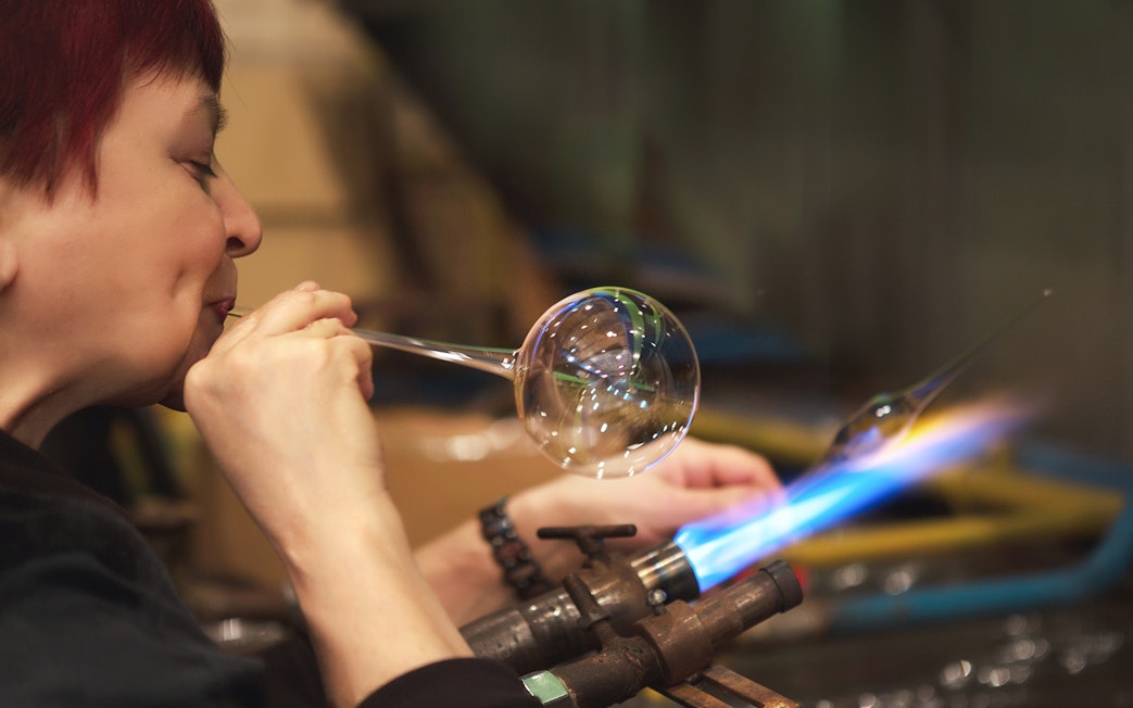 Glassblower shaping glass at Murano factory demonstration.