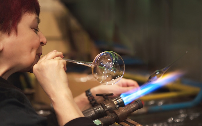 Glassblower shaping glass at Murano factory demonstration.
