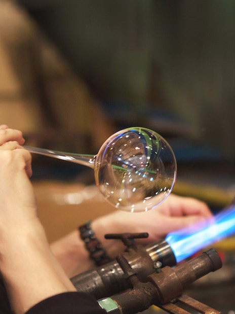 Glassblower shaping glass at Murano factory demonstration.