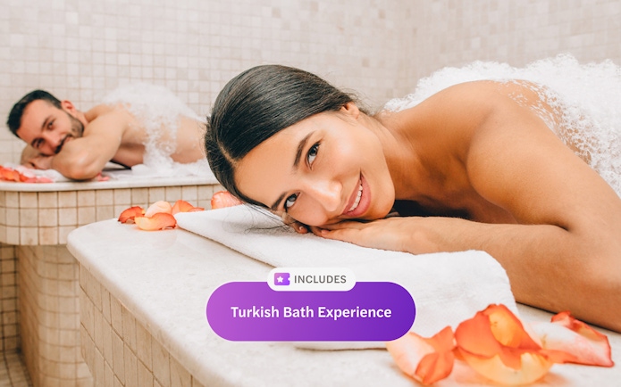 Woman relaxing in a Turkish bath with rose petals.