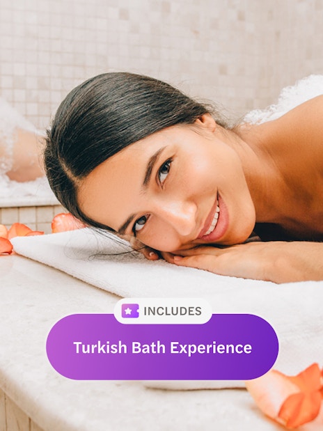 Woman relaxing in a Turkish bath with rose petals.