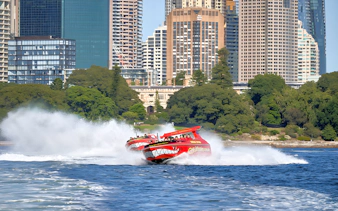 Jet boats speeding on Sydney Harbour with city skyline in the background.