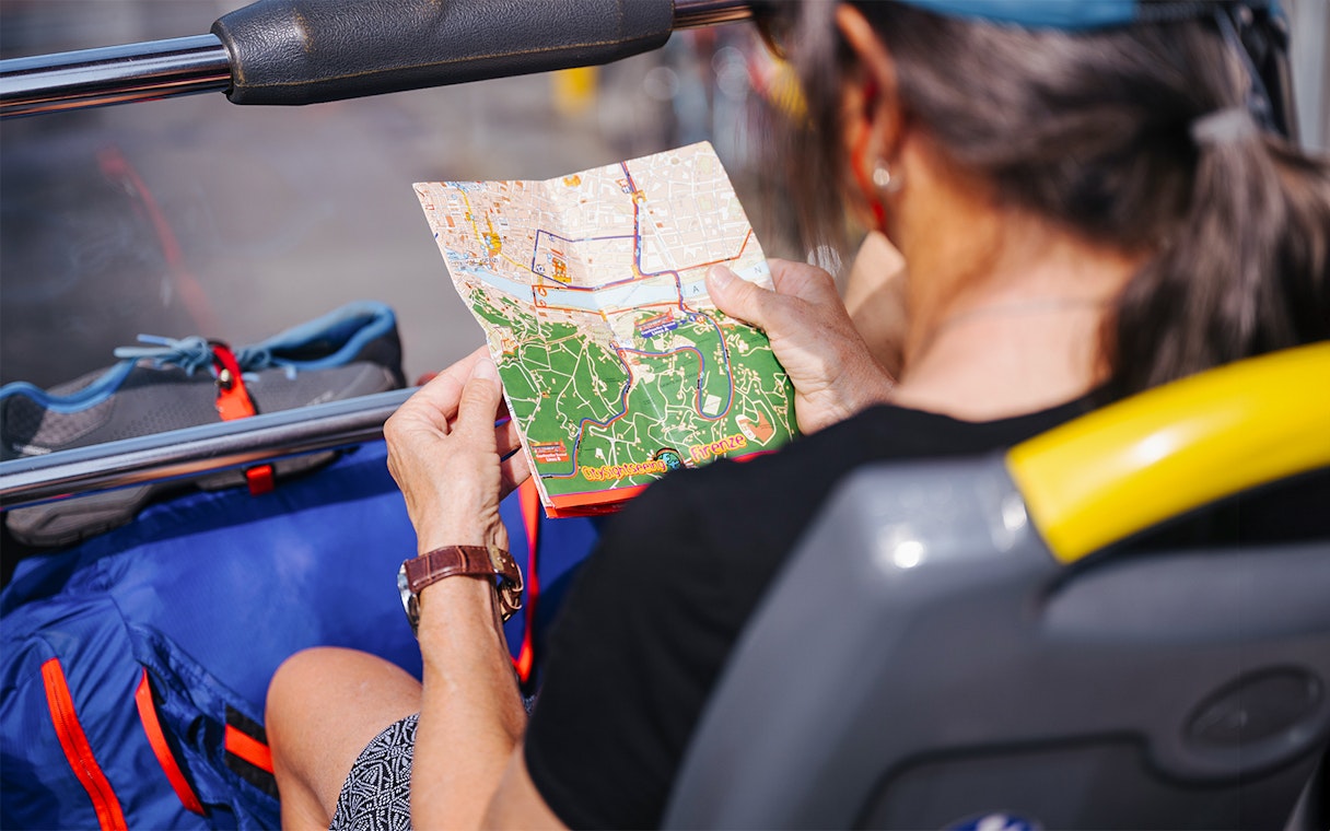 Passenger on HOHO bus in Milan examining route map.