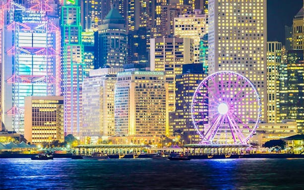 Hong Kong skyline with illuminated Ferris wheel during Star Ferry Harbor Tour.