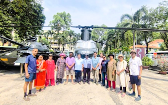 Group of tourists in front of a helicopter at a historical site in Ho Chi Minh City.