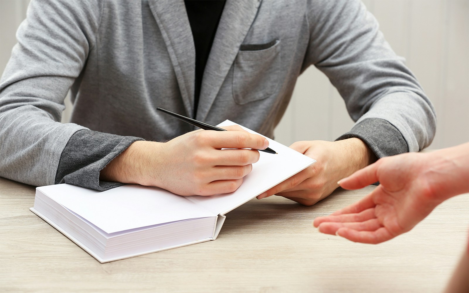 Signing an autograph in a book at a table.