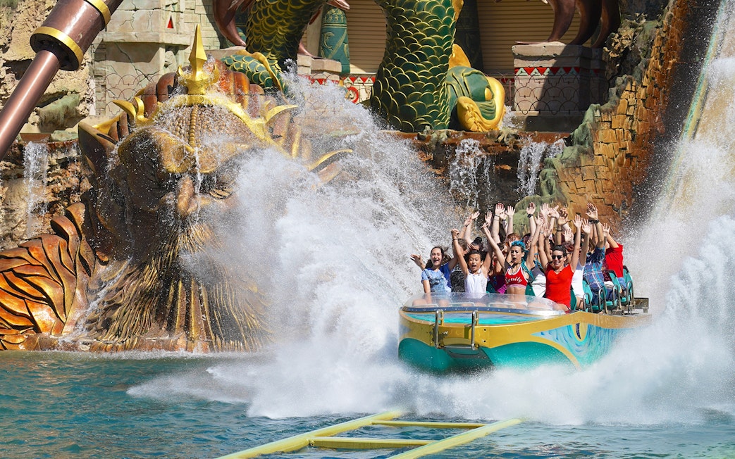 Visitors enjoying a thrilling water ride at Gardaland Park with a dragon sculpture backdrop.