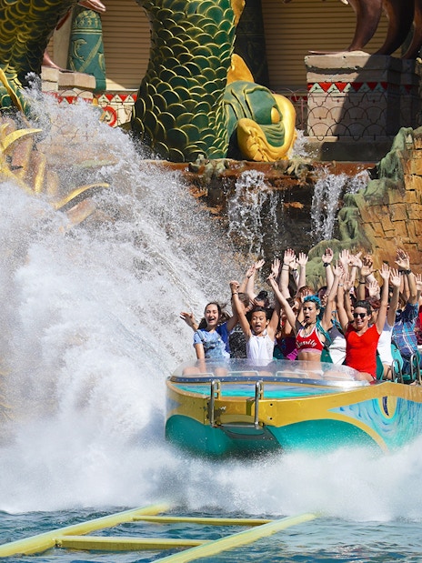 Visitors enjoying a thrilling water ride at Gardaland Park with a dragon sculpture backdrop.