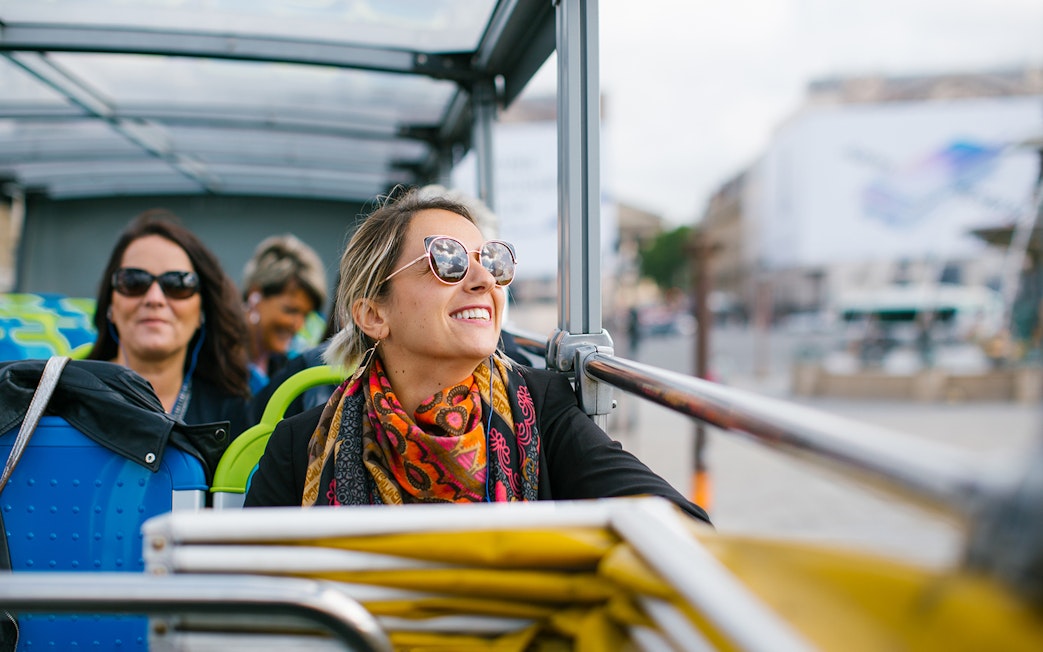 Woman enjoying a hop-on hop-off bus tour in Paris.