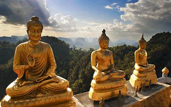 Golden Buddha statues at Tiger Temple, Krabi, with lush jungle backdrop.