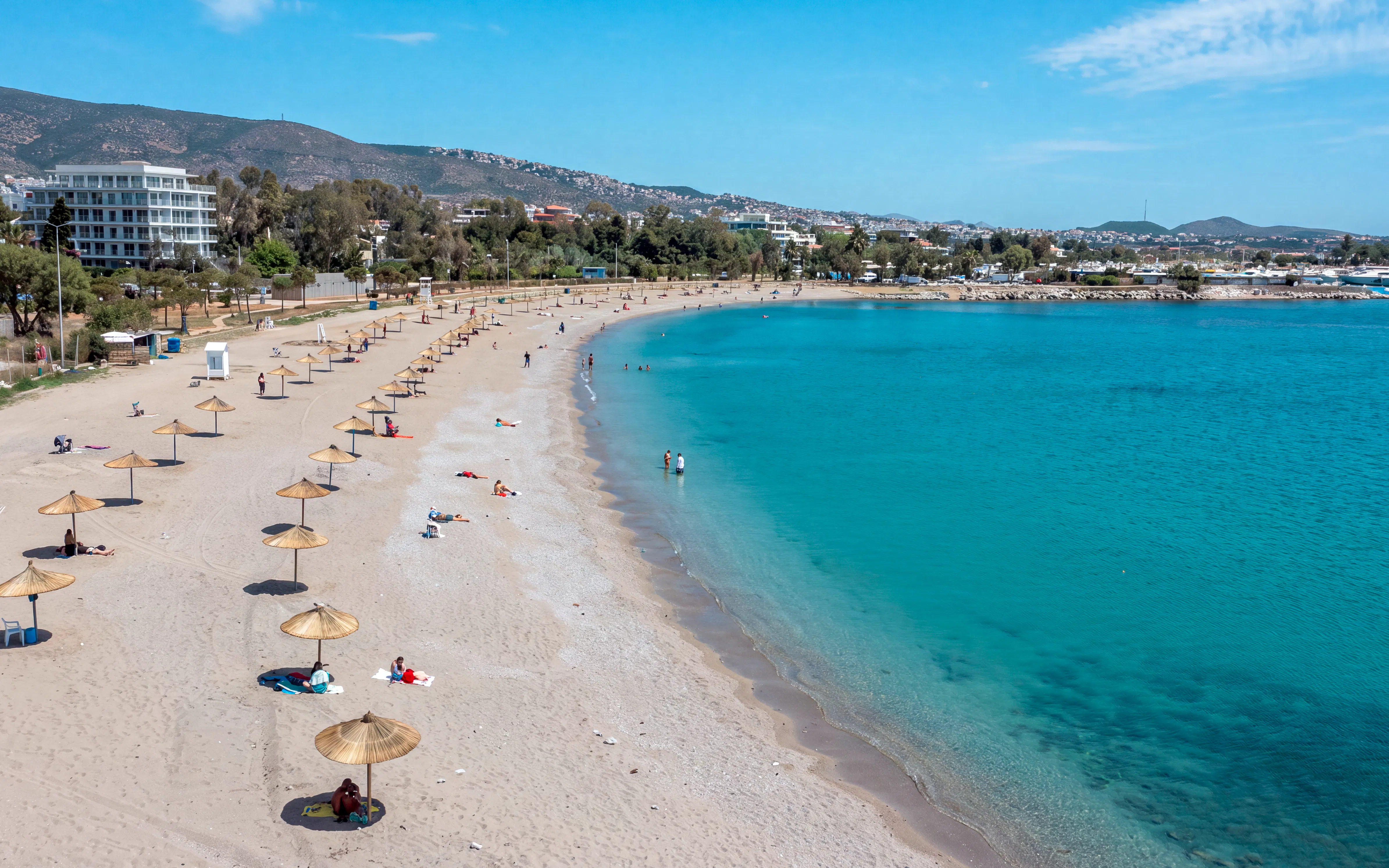 Beach with umbrellas and people relaxing, part of Sounion Half-Day Tour, Greece.