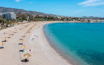 Beach with umbrellas and people relaxing, part of Sounion Half-Day Tour, Greece.