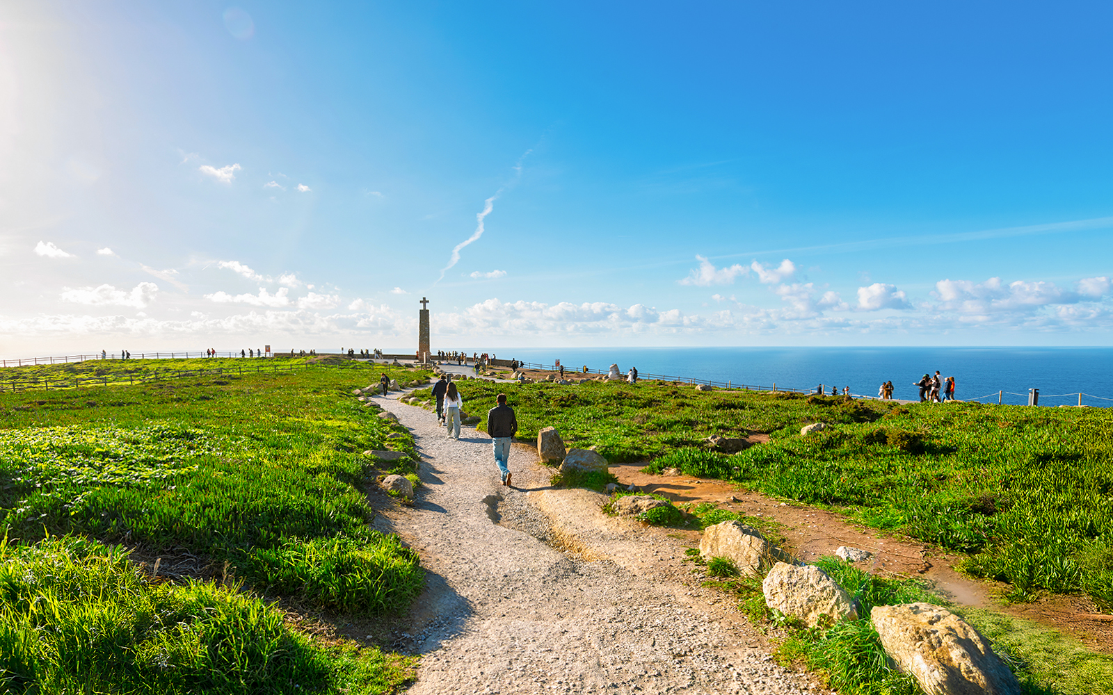 Tourists walking along a path with Atlantic Ocean view at Cabo de Roca, Portugal.