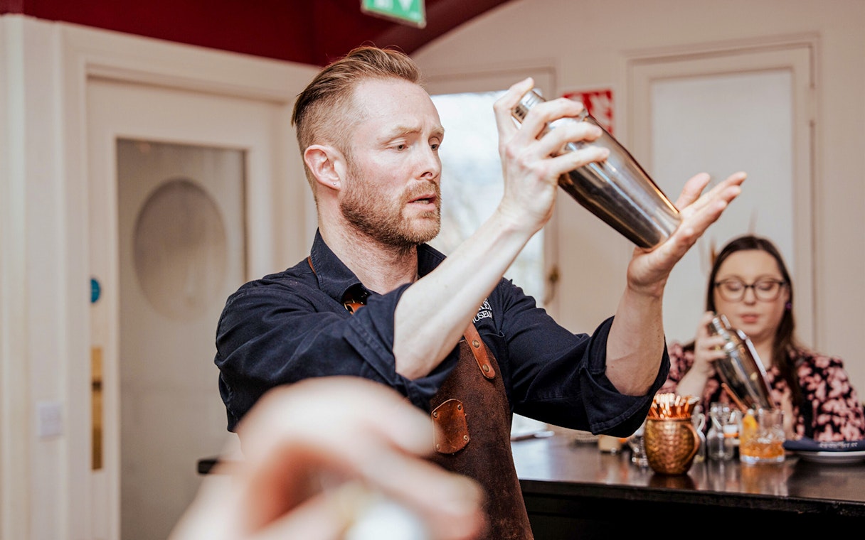 Bartender demonstrating cocktail shaking at the Irish Whiskey Museum masterclass.