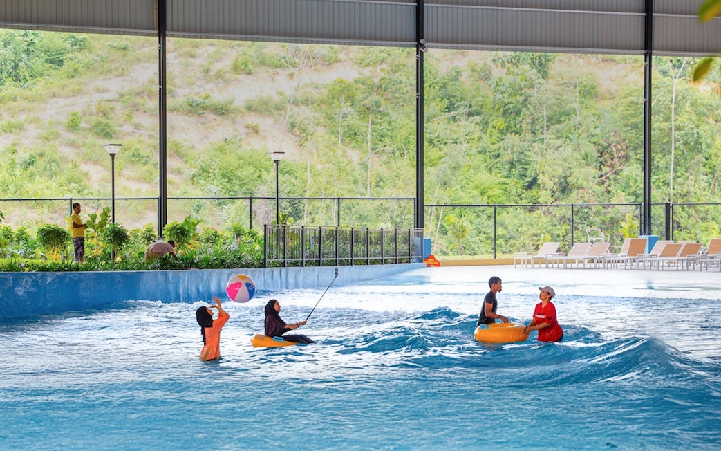 Children enjoying a wave pool with inflatable tubes and a beach ball.