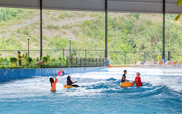 Children enjoying a wave pool with inflatable tubes and a beach ball.