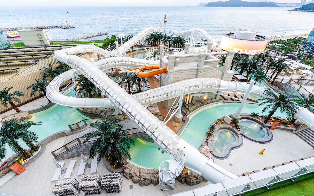 Overhead view of intertwining waterslides at Club D Oasis water park overlooking the sea.
