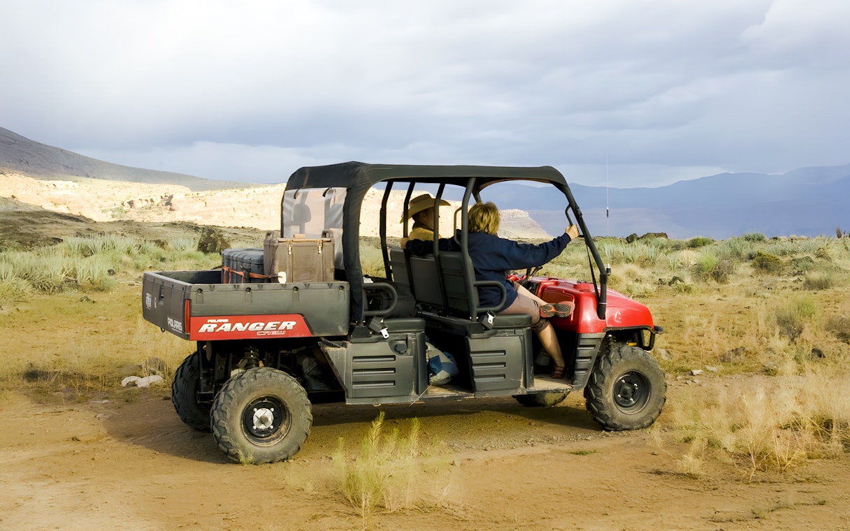 Guests riding a Polaris Ranger through a desert landscape.