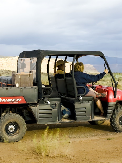 Guests riding a Polaris Ranger through a desert landscape.
