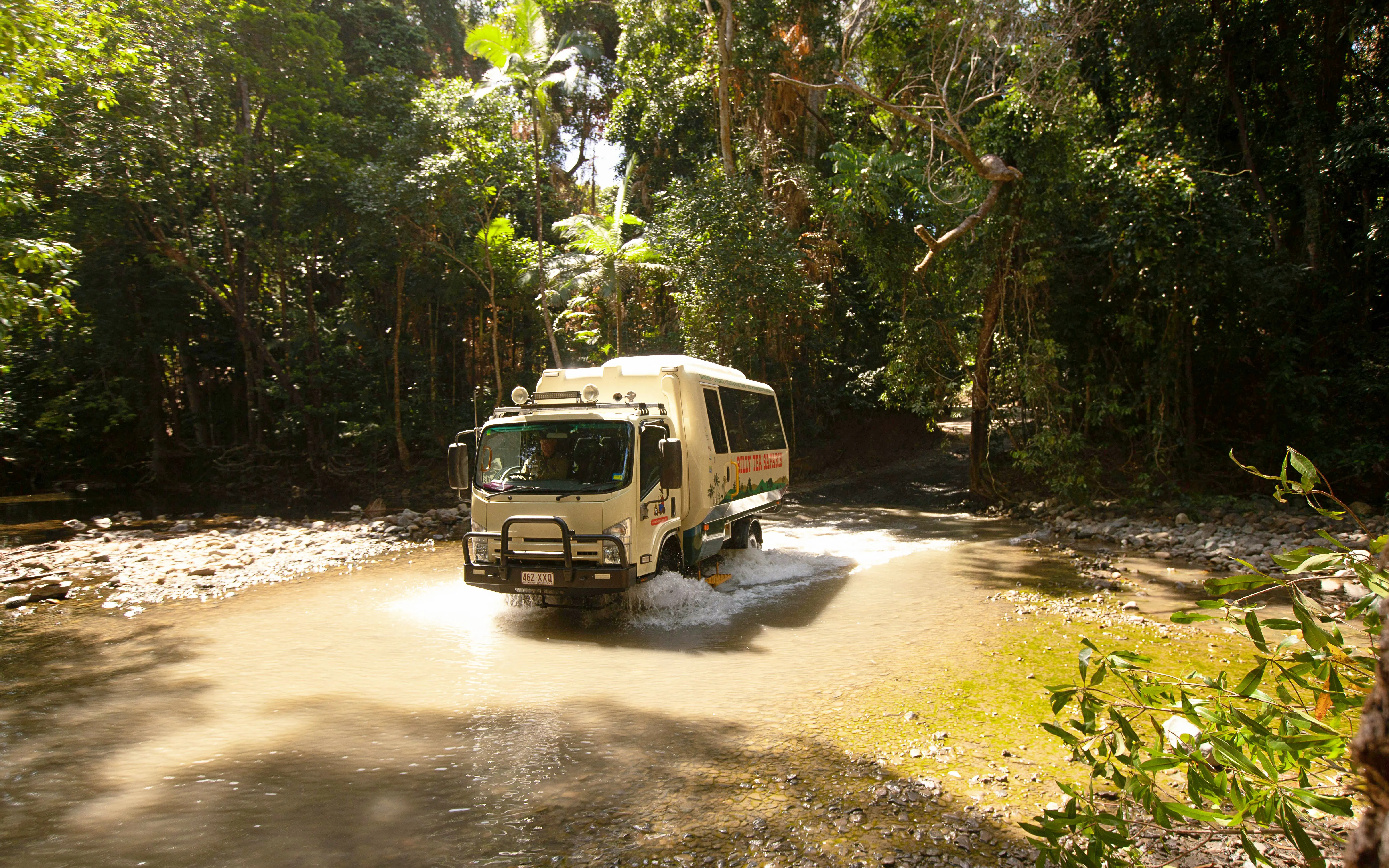 Tour bus crossing a stream in Daintree Rainforest, part of the 2-day Great Barrier Reef tour from Cairns.