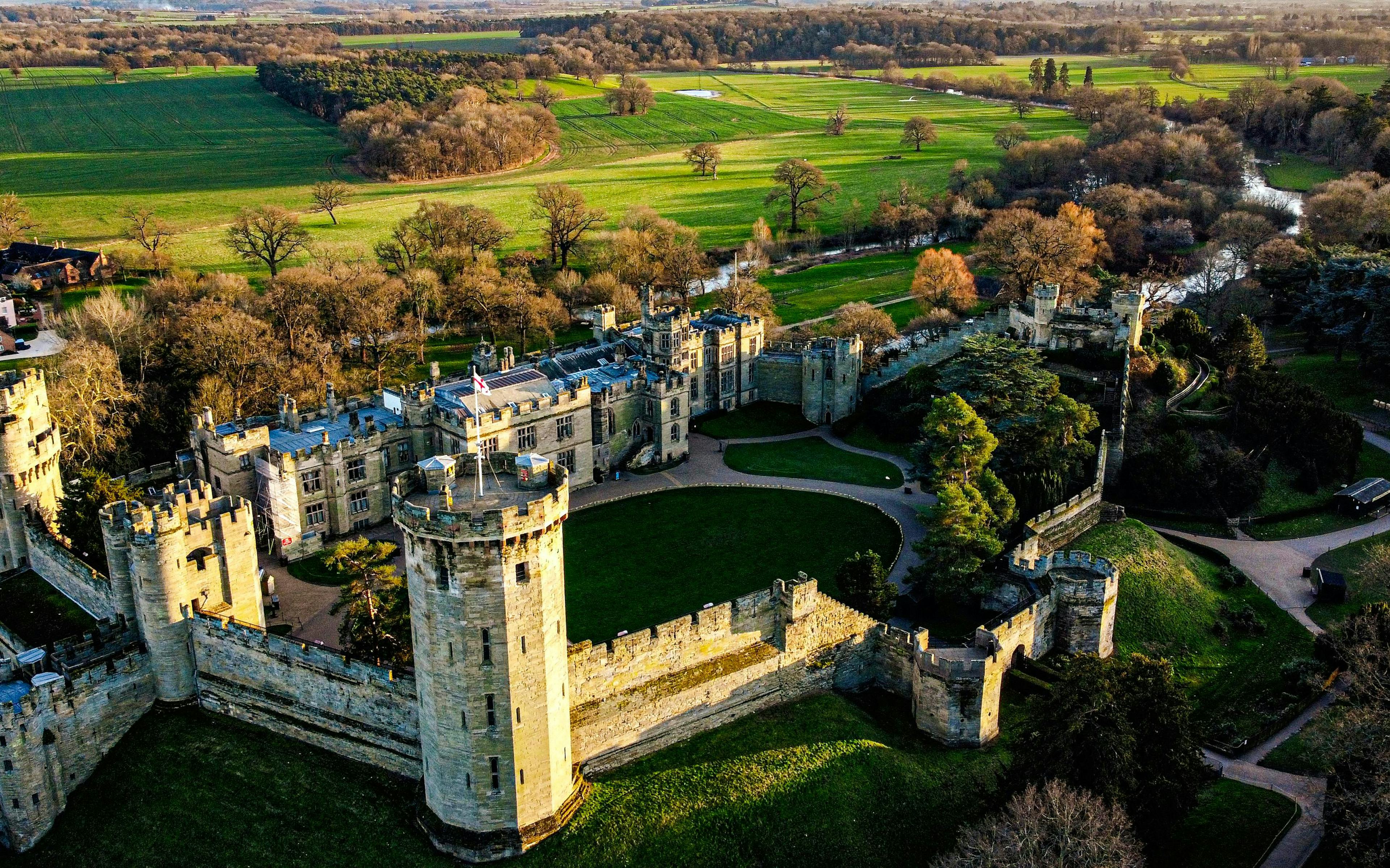 Aerial view of Warwick Castle surrounded by lush green landscape.