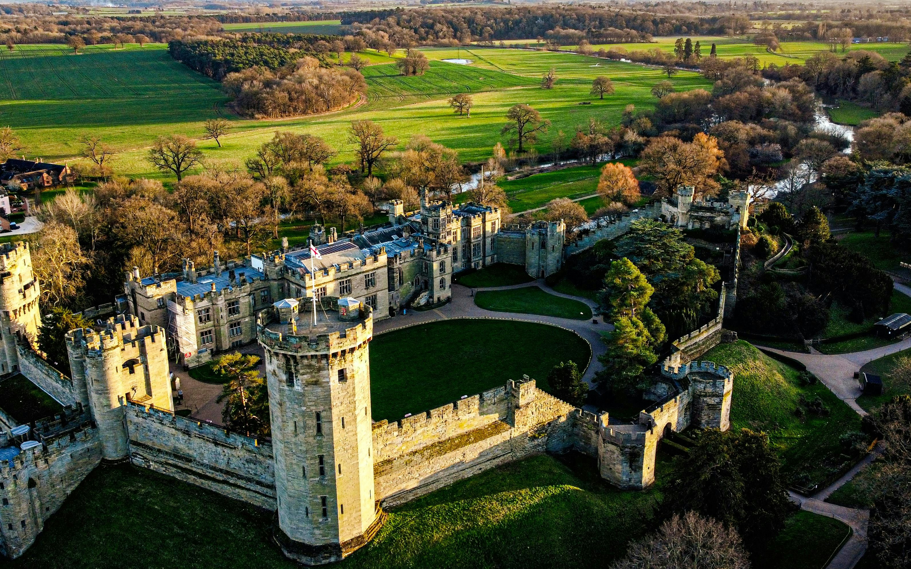 Aerial view of Warwick Castle surrounded by lush green landscape.
