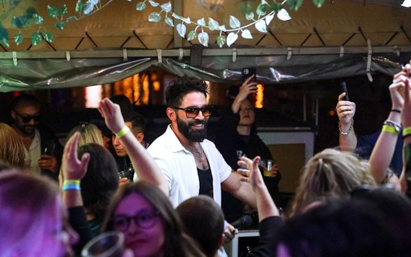 DJ performing at a lively boat cruise party in Prague with guests dancing.