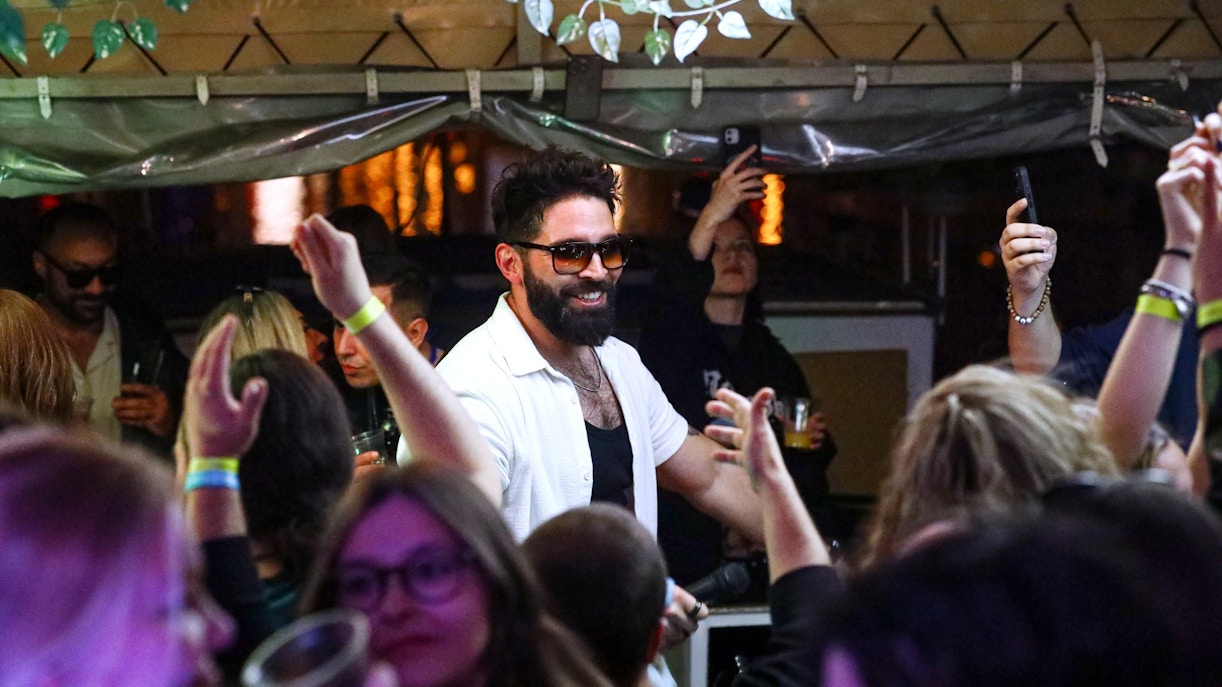 DJ performing at a lively boat cruise party in Prague with guests dancing.