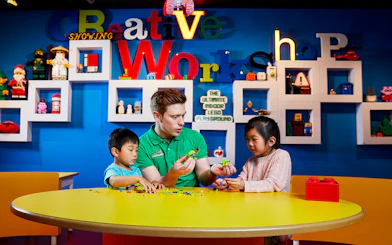 Children building LEGO models with instructor at LEGOLAND Discovery Centre.