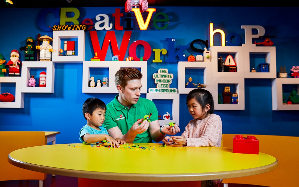 Children building LEGO models with instructor at LEGOLAND Discovery Centre.