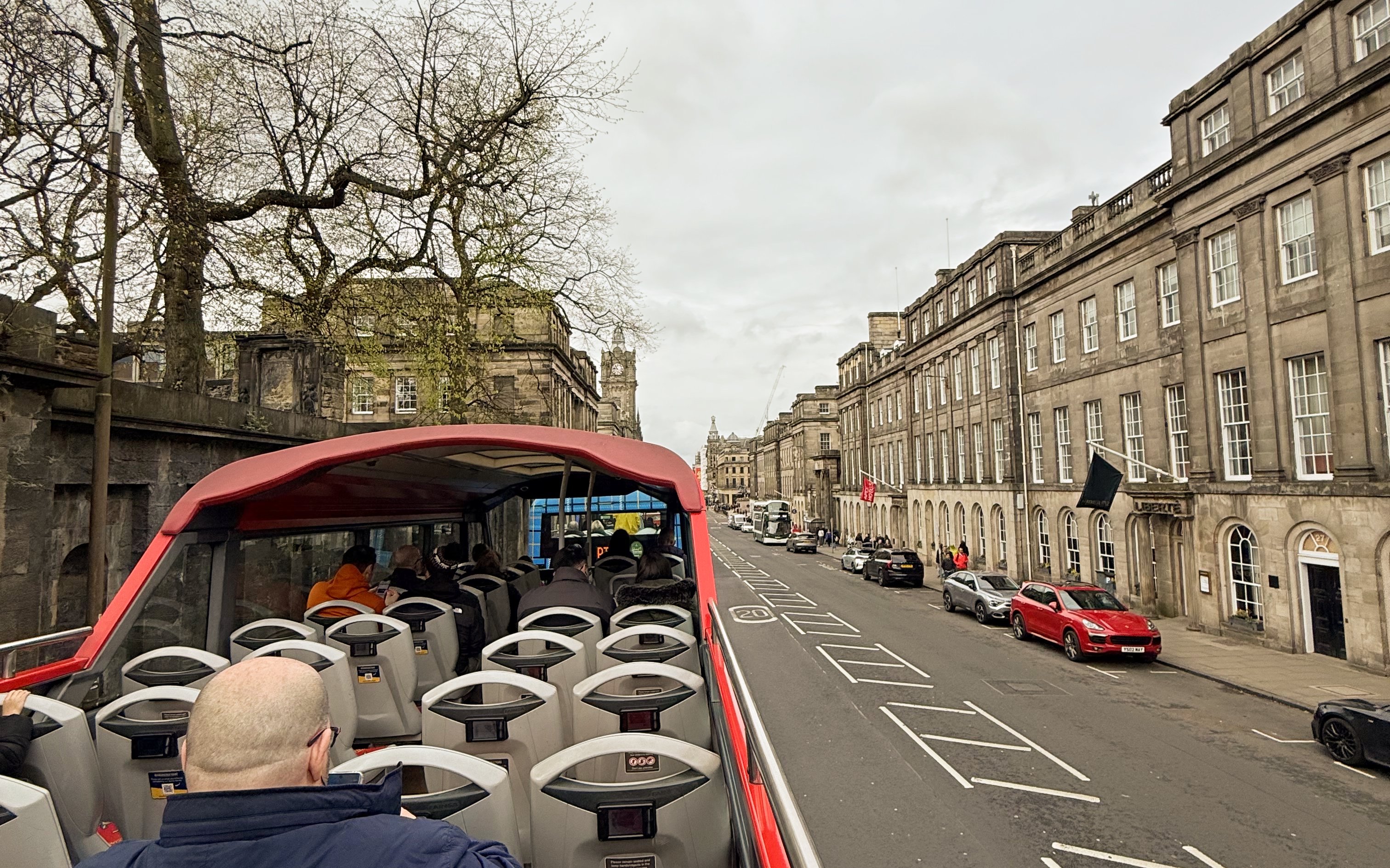 Open-top bus on Edinburgh street during hop-on hop-off tour.