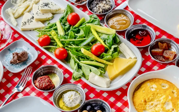 Turkish breakfast spread with cheese, greens, and condiments on a Bosphorus cruise table.
