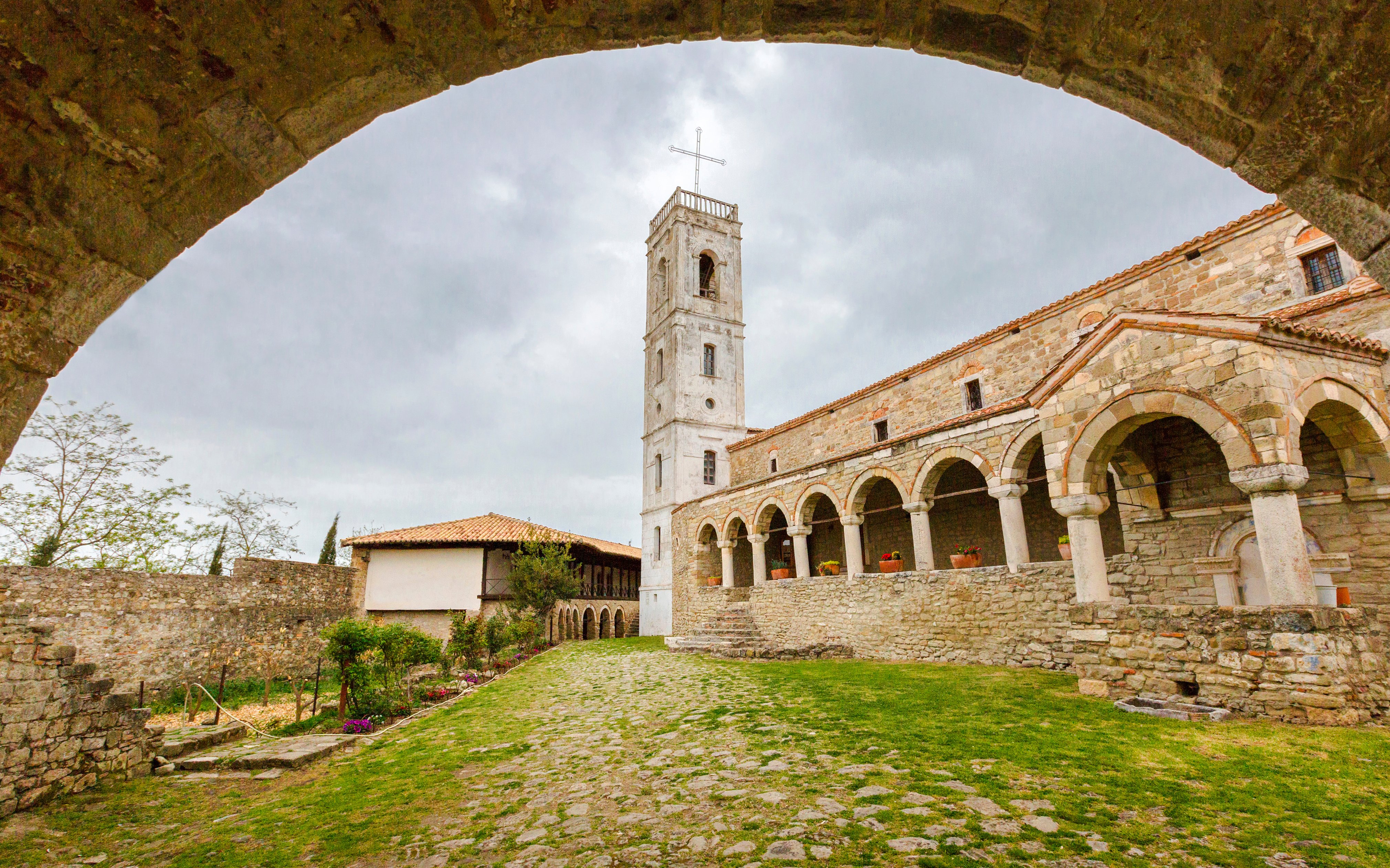 Church of Ardenica courtyard with stone arches and bell tower.
