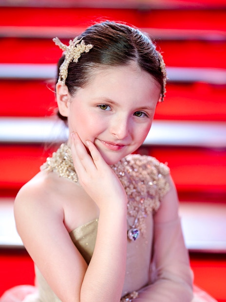 Girl posing at Times Square with red steps in the background.