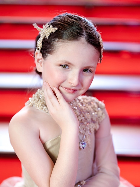 Girl posing at Times Square with red steps in the background.